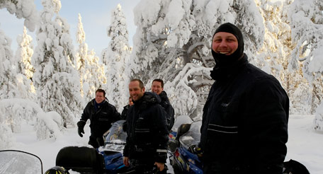 Group of snowmobilers standing next to snowmobiles