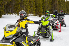 Snowmobilers riding trails showing hand signals